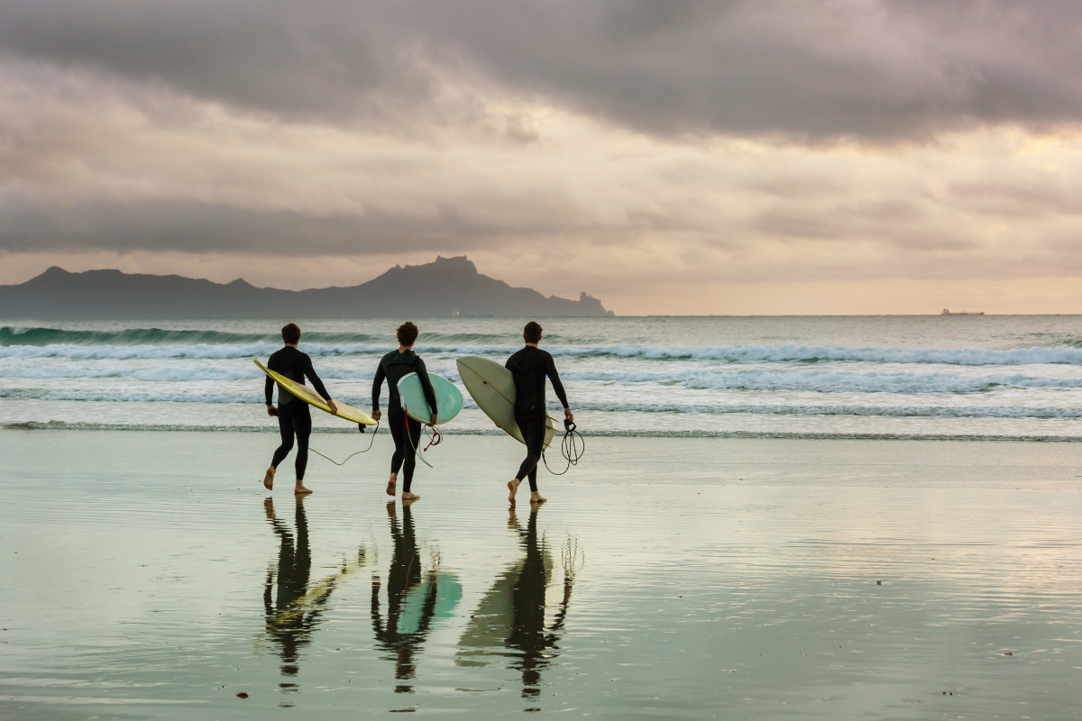 Surfers walking down to a right hand point break at first light
