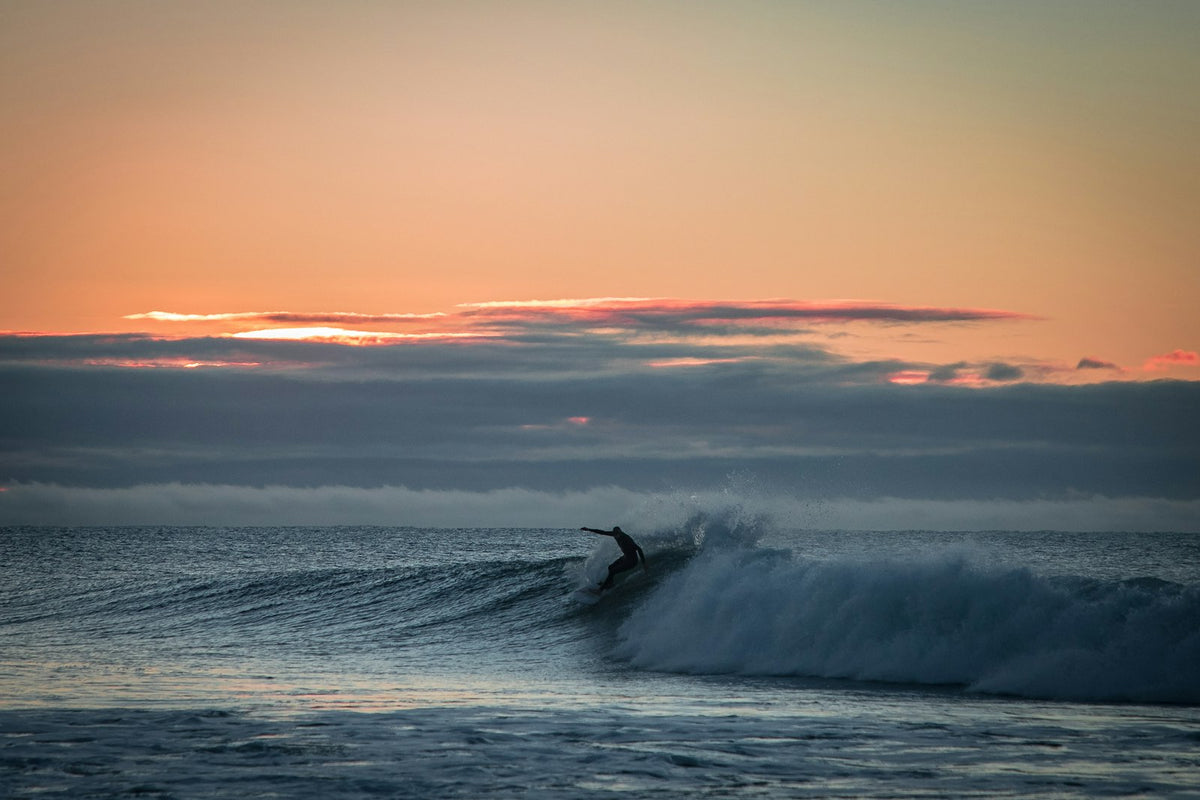 Surfeur sur une vague au lever du soleil à Bells Beach, dans l’État de Victoria, en Australie