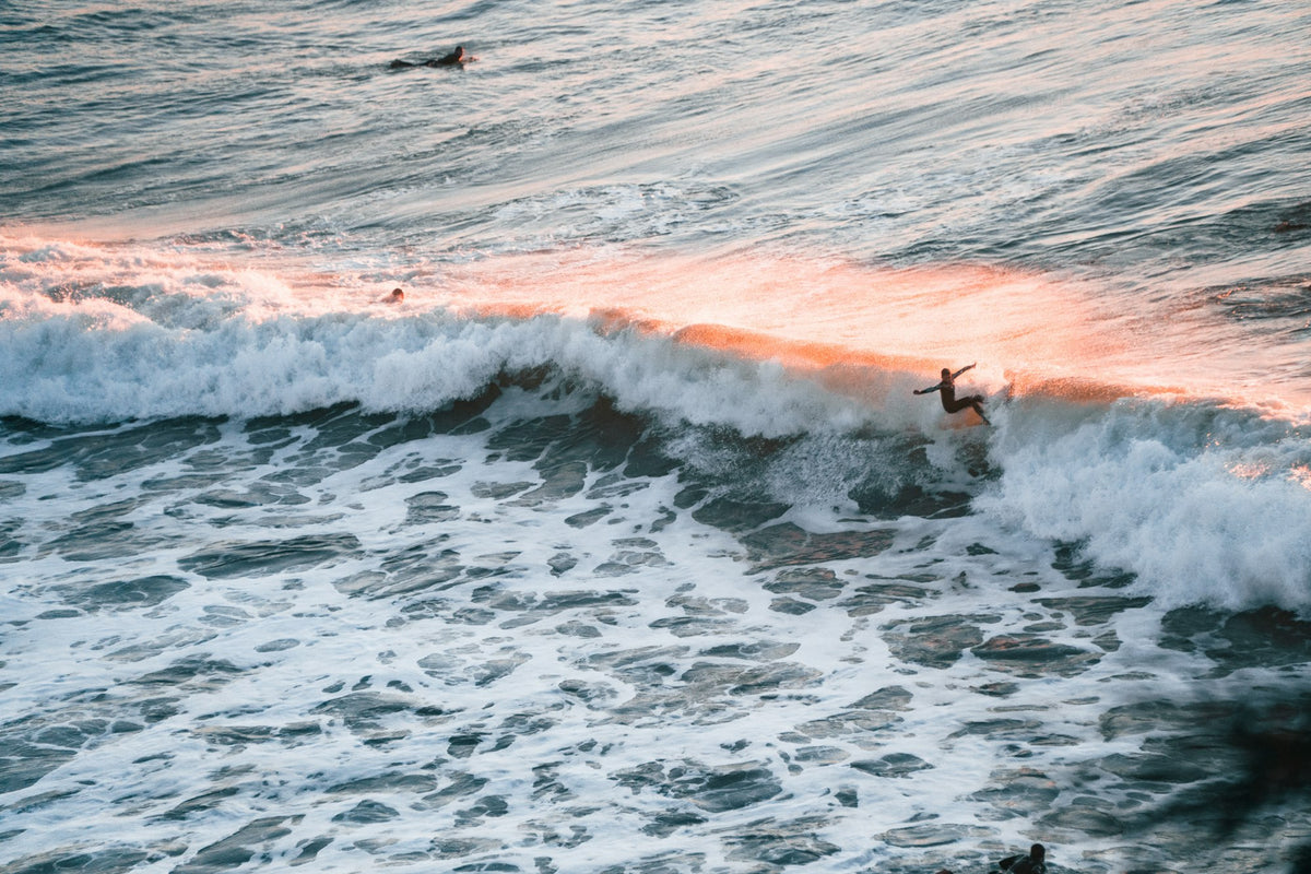 Surfer riding a wave at sunset in Ericeira, Portugal