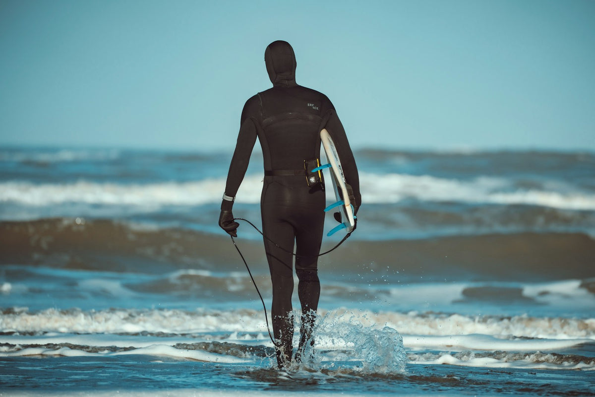 Surfer in a winter wetsuit walking into the sea with a surfboard at Terschelling, the Netherlands