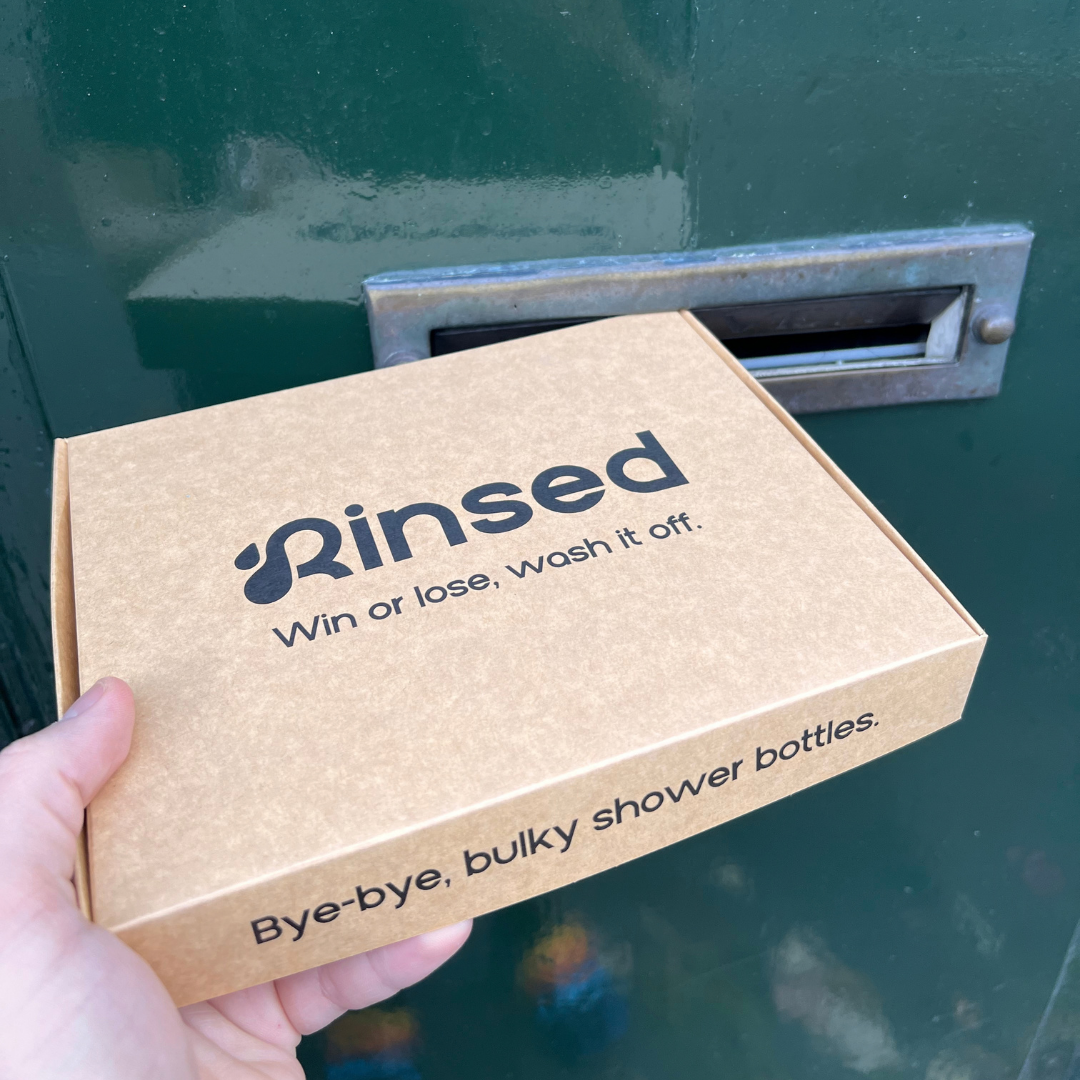 Hand holding the Rinsed™ gift box in front of a letterbox