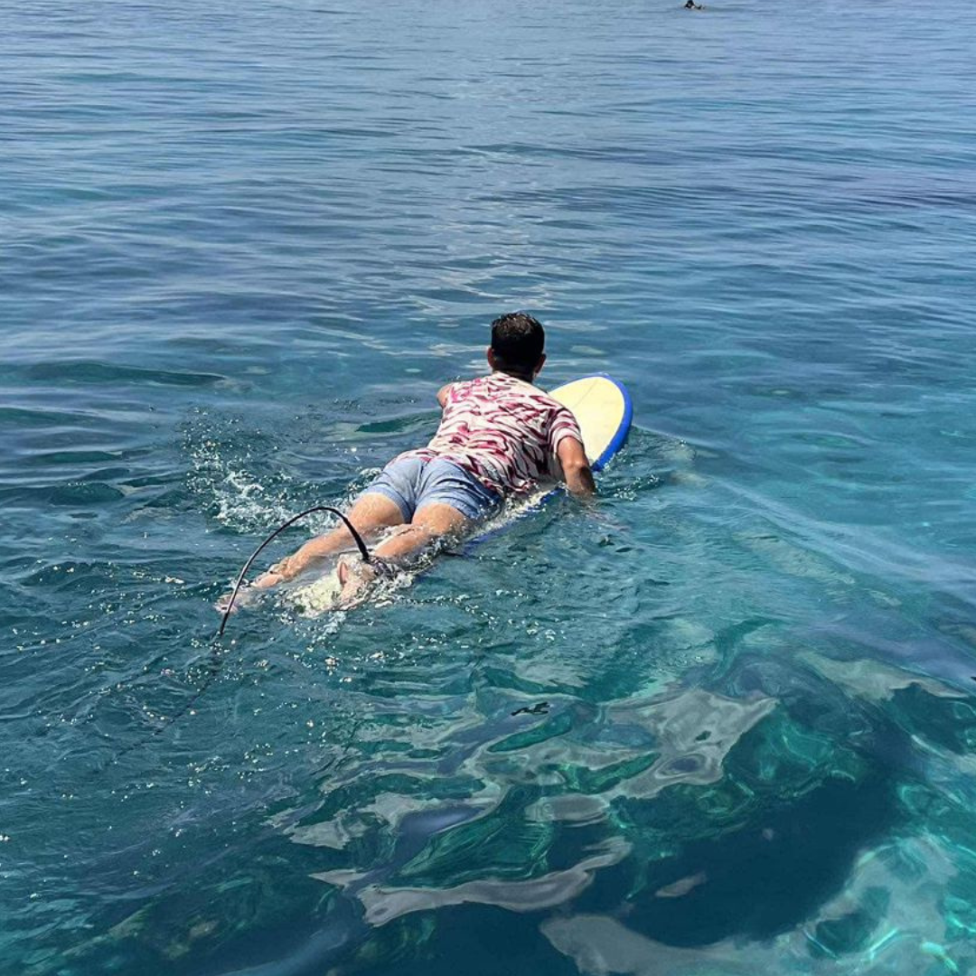 man paddling on surf board in clear water