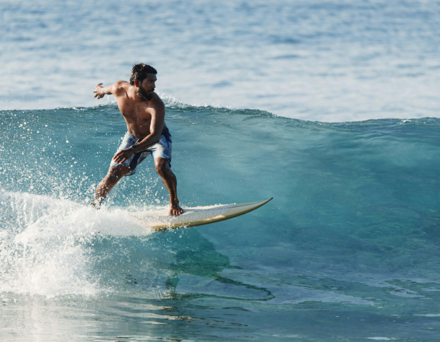 Surfer riding a turquoise wave in the Maldives, a top surf destination in June