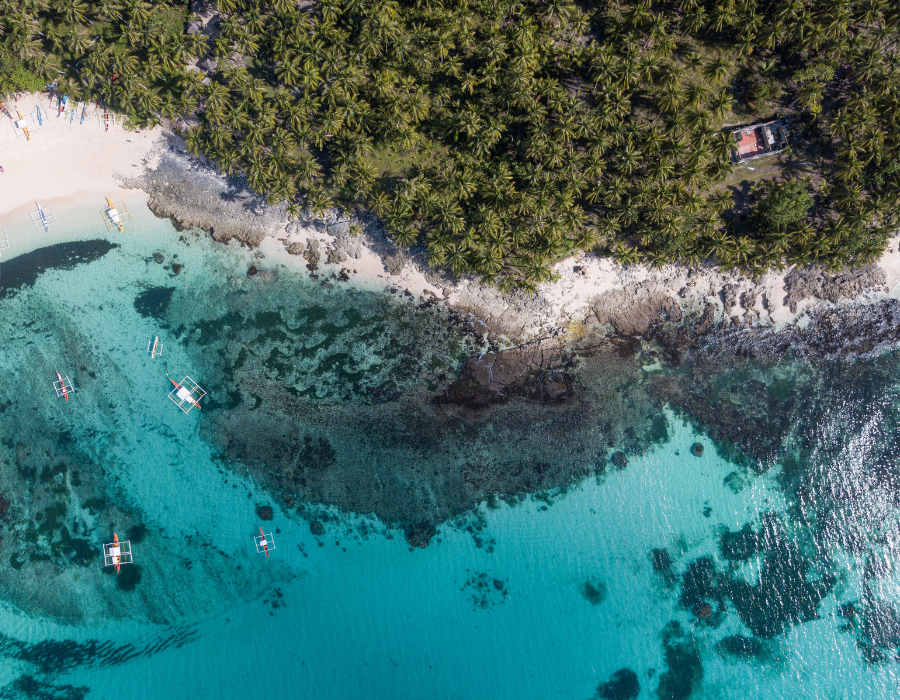 Aerial view of turquoise water and a white sand beach at Daku Island, Siargao