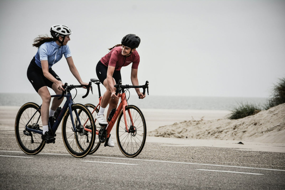 Two cyclists on road bikes near the shore