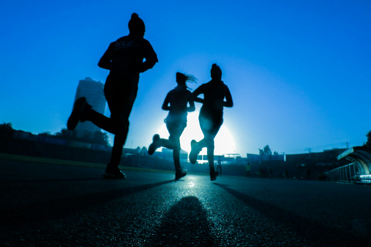 Three runners on a road at sunrise