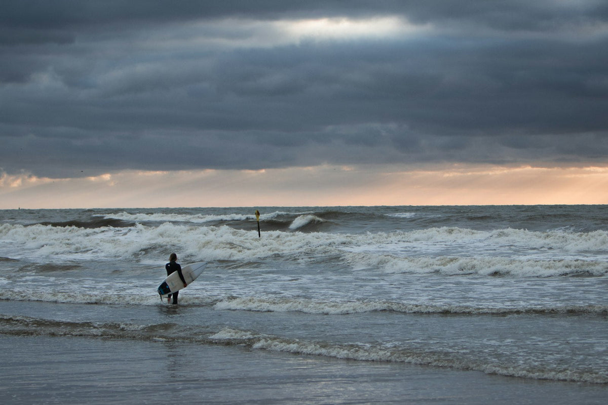 Surfer loopt met een surfplank over het strand van Scheveningen, Nederland