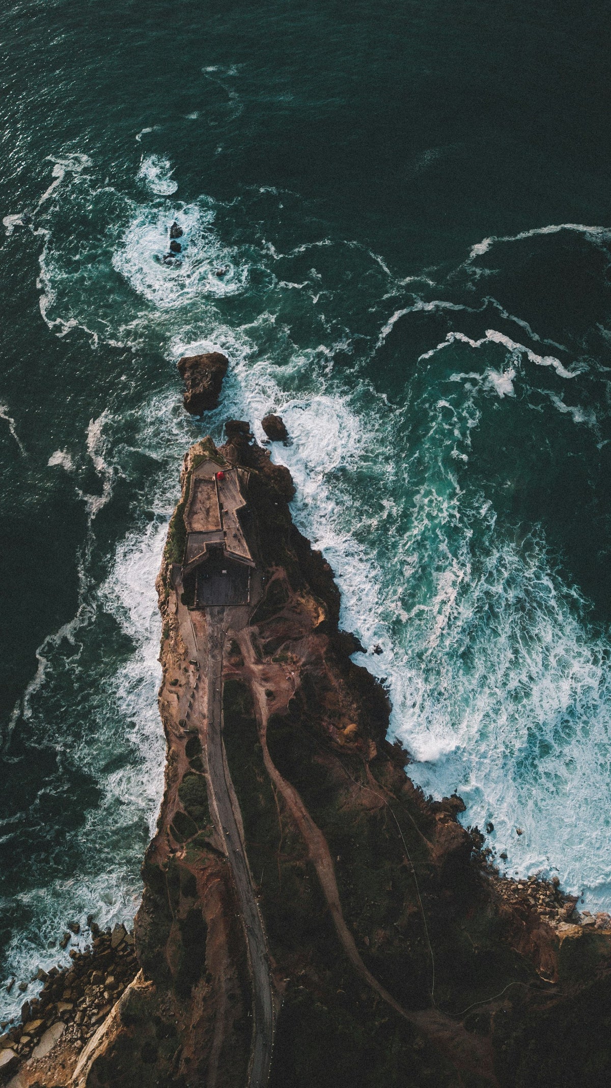 Aerial view of a lighthouse on a rocky shore in Nazaré, Portugal