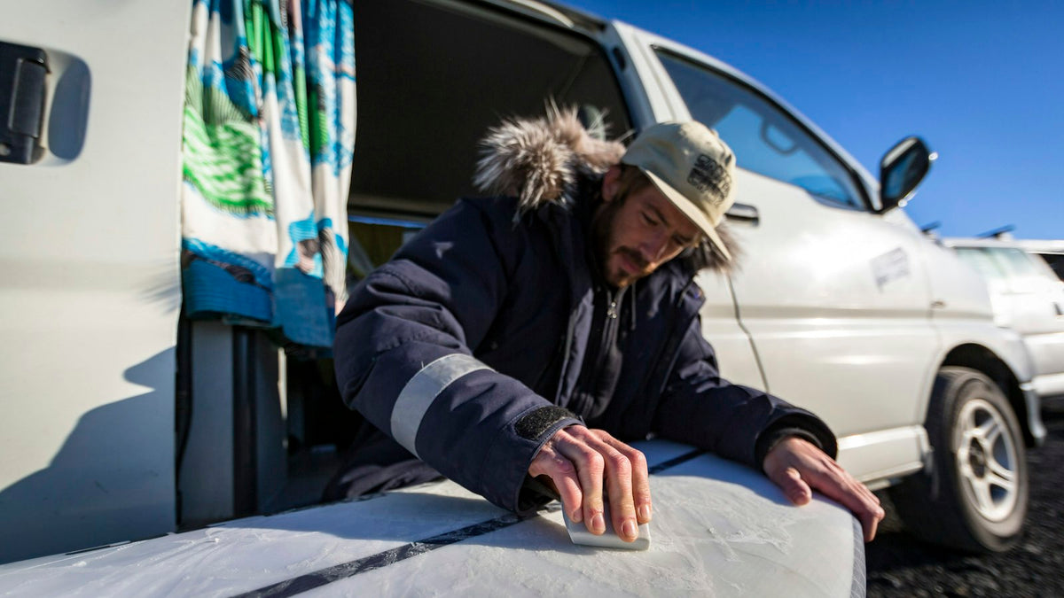 Man laadt een surfplank in een camperbusje