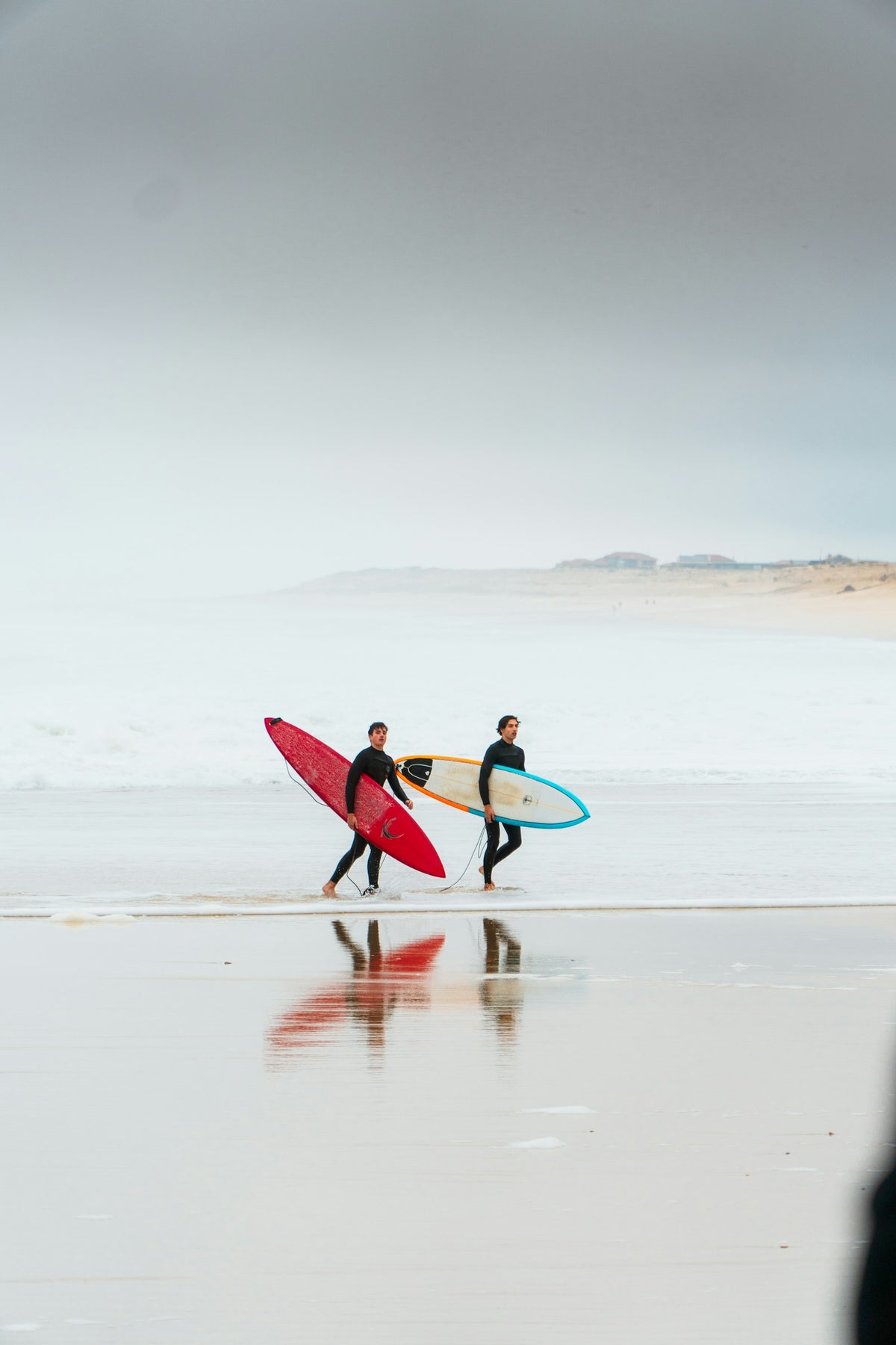 Two surfers walking on the beach with their surfboards in Hossegor, France