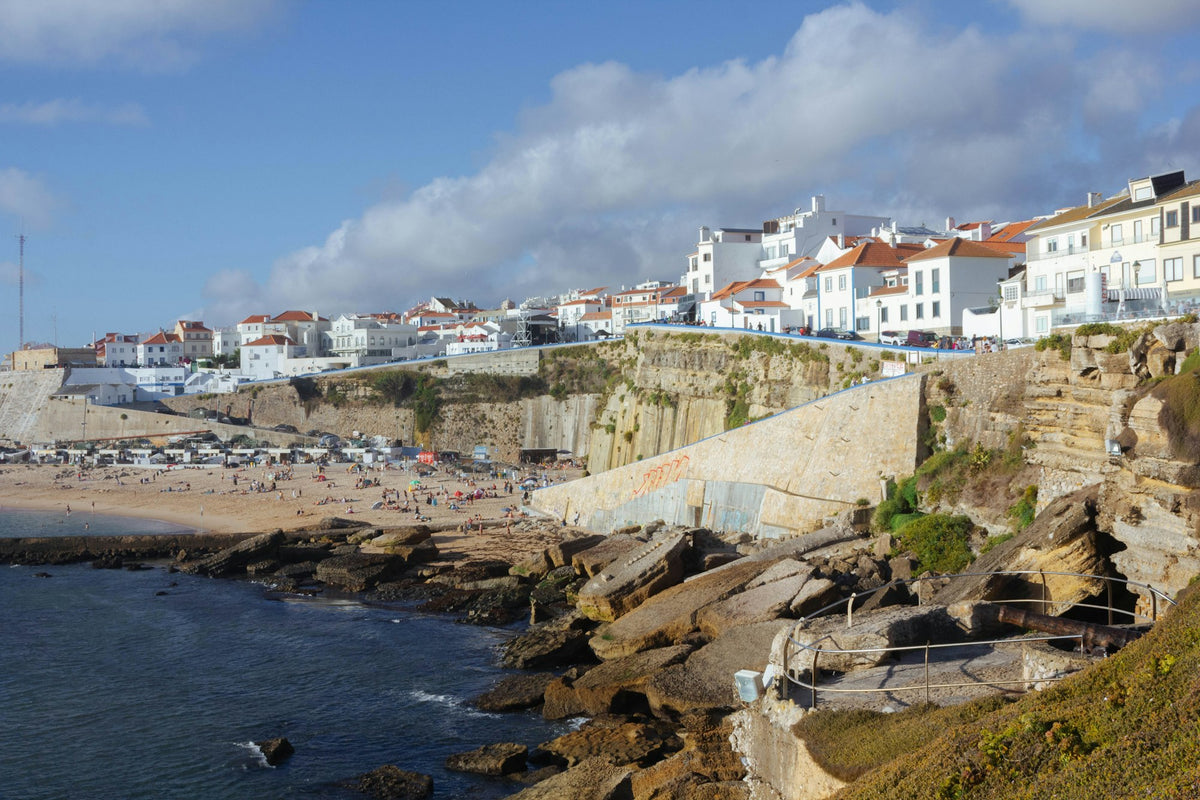 Beach in Ericeira, Portugal, with the town's buildings on the cliff behind