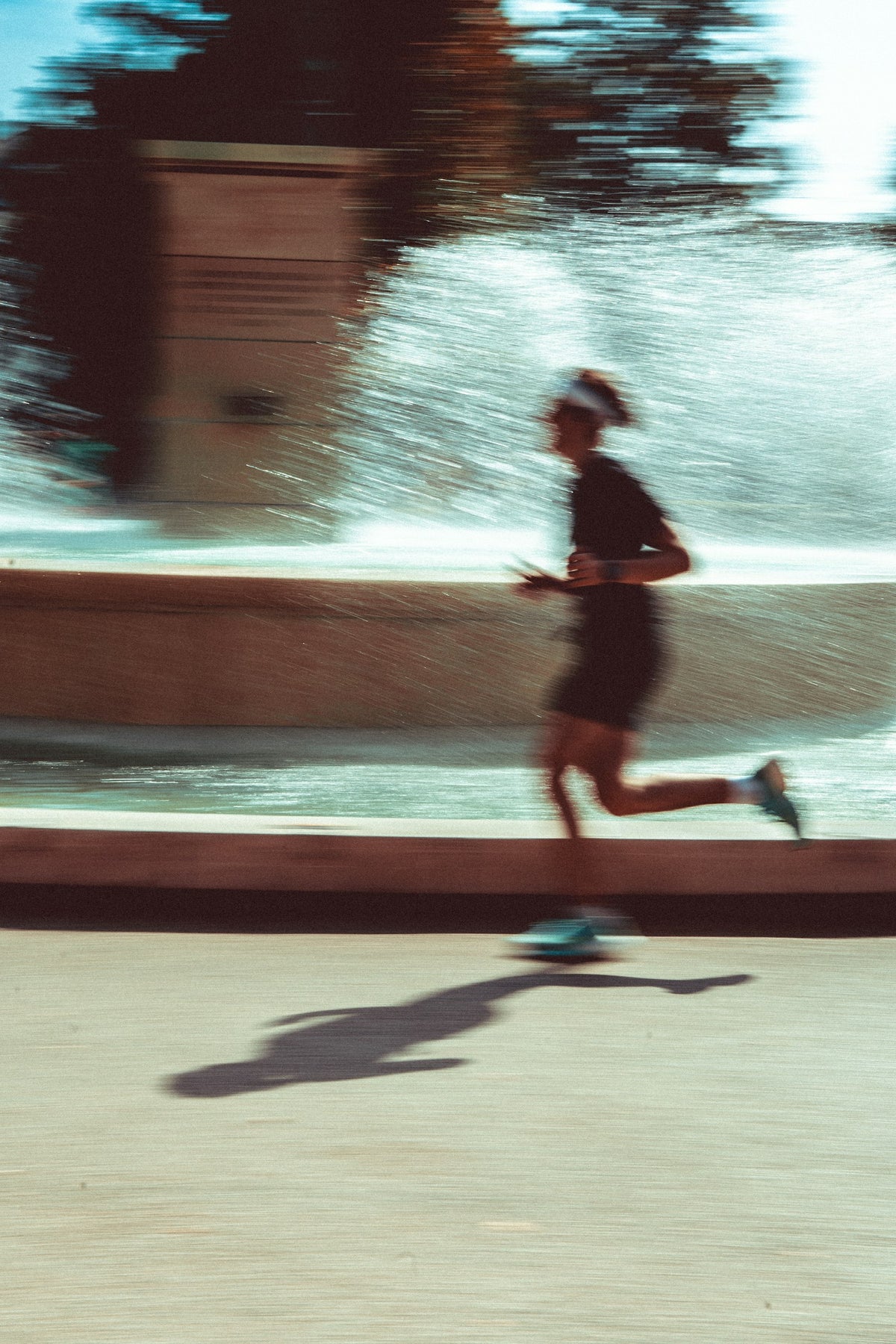 Man running down a city street past a fountain