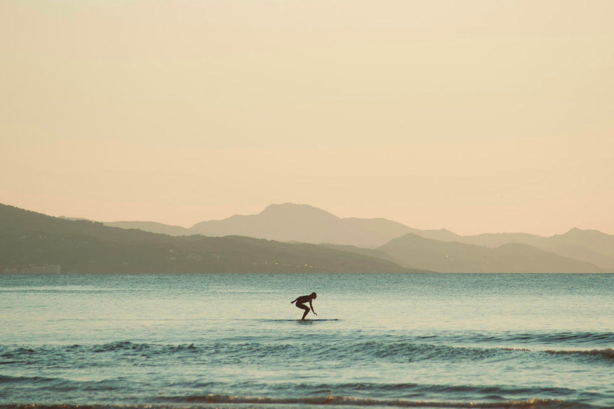 Surfer riding a wave at sunset in Biarritz, France