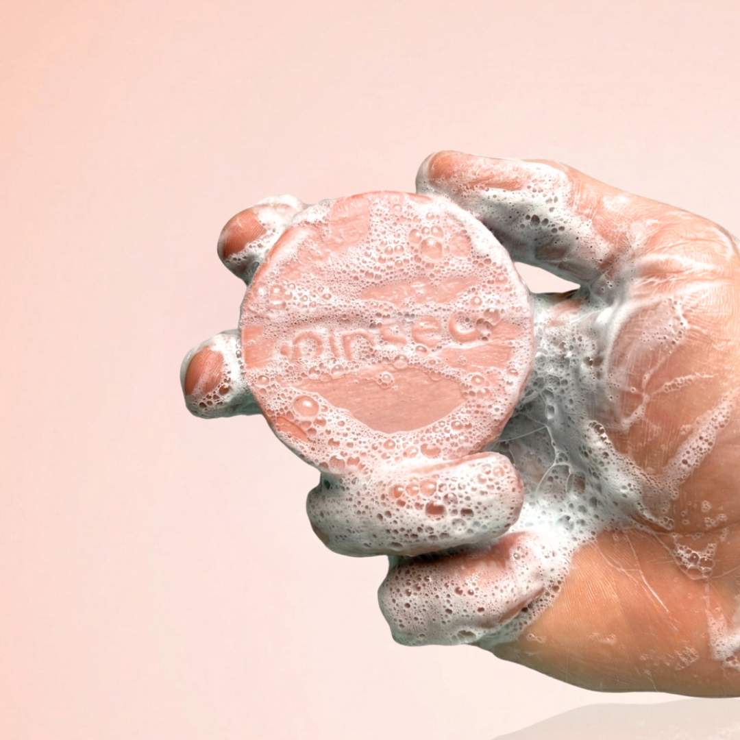 Hand holding a foamy pink Blossom Blast 3-in-1 bar from Rinsed™