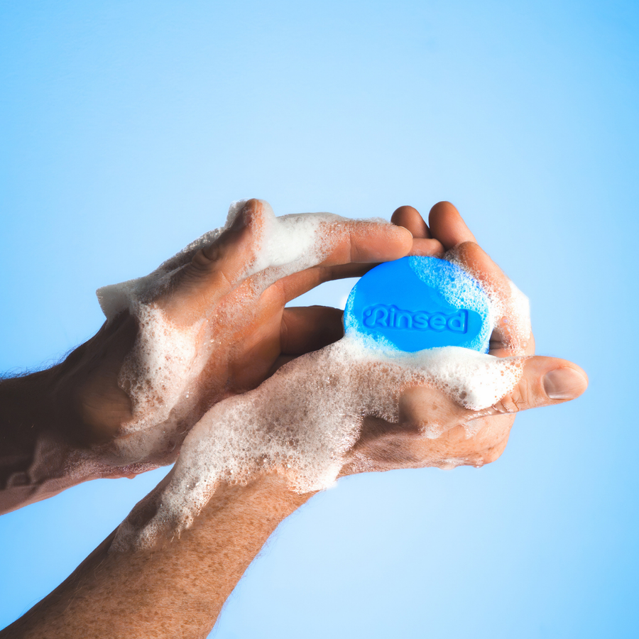 Hands lathering a blue Minty Cactus 3-in-1 bar from Rinsed™ into foam