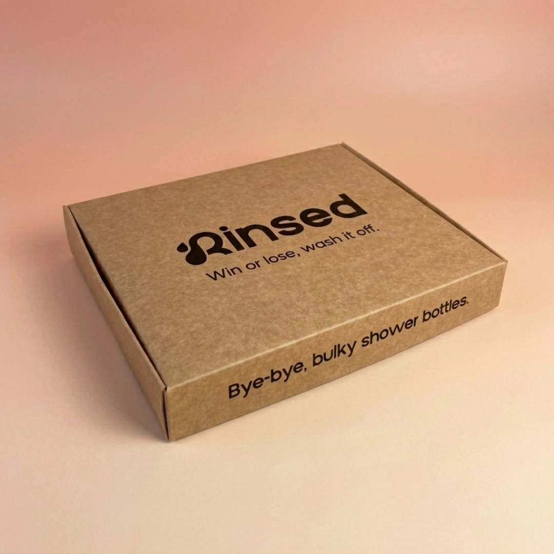 Rinsed™ gift box seen from the side, reading Bye-bye, bulky shower bottles, on a pink background